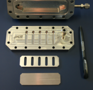 Mikrostrukturierter Reaktor in Bestandteile zerlegt: Reaktorgehäuse mit Deckel, Distanzstück, Blindfolie zur Aufnahme eines Thermoelements und Mikrostrukturfolie mit der erzeugten katalytischen Beschichtung. (Bild: Institut für Mikroverfahrenstechnik / KIT)