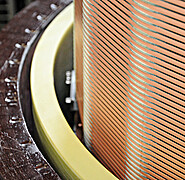 A close-up view of the coil shows the pre-wound superconductor bands running along the horizontally run grooves.