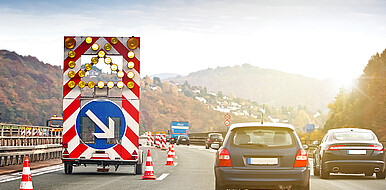Mehrere Fahrzeuge fahren auf drei Fahrbahnen mit einer Wanderbaustelle links in engem Abstand nebeneinander. Die Perspektive ist die des dahinterfahrenden Fahrzeugs, dessen Radar die Situation gut detektieren muss. (Bild: Tom Bayer / Adobe Stock)