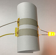 Trotz reduziertem Anteil an metallischen Partikeln ist die gedruckte Elektronik leitfähig und das LED-Lämpchen leuchtet.