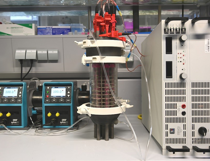 Erster Testaufbau des skalierbaren Partikelelektrodenreaktors mit einem Reaktorvolumen von 1 L. Das Reaktionssystem ist an ein regelbares Netzteil angeschlossen, sowie an zwei Pumpensystemen zur Bereitstellung der Reaktionslösungen für den Gegen- und Arbeitselektrodenraum. (Bild: IFG)