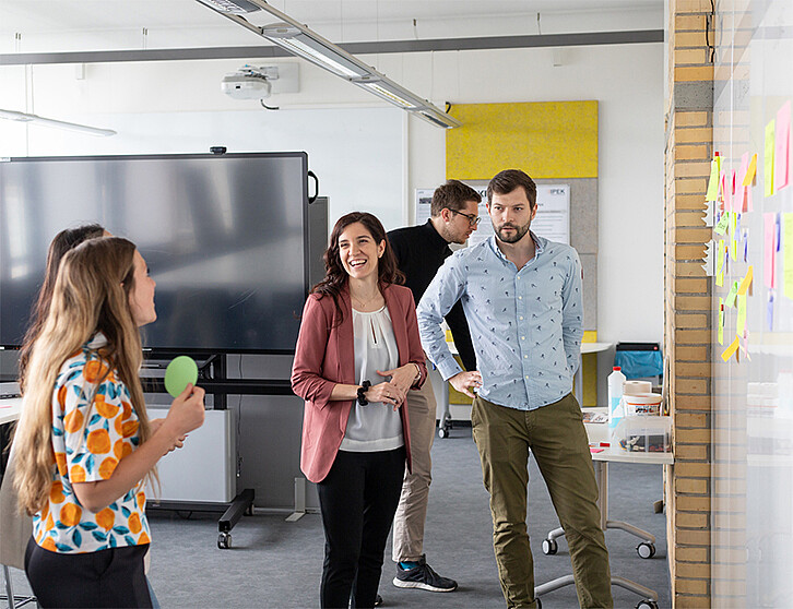 People in an office discussing in front of a whiteboard with colorful sticky notes – scene from a collaborative workshop. (Image: Institute of Product Engineering / KIT)