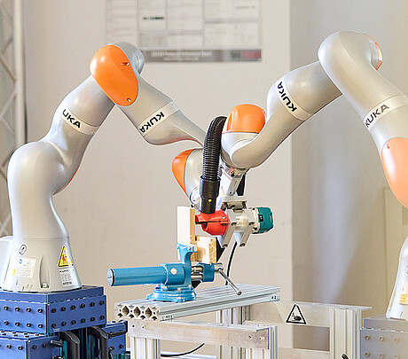 Zwei Roboter arbeiten als kollaborierende Roboter im Team: Mit geteilten Kräften führen sie gemeinsam eine Fertigungsaufgabe aus. Solche Multi-Roboter-Systeme haben das Potenzial, industrielle Fertigungsprozesse flexibler zu gestalten. (Bild: KIT)