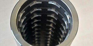 Blick in das Innere eines Metallrohrs mit ca. sieben Zentimeter Durchmesser. Die Innenwände sind in regelmäßigen Abständen mit punktuell angebundenen Flügelprofilen besetzt. Diese Struktur ist durch konventionelle Verfahren nur begrenzt realisierbar. (Bild: Heiko Neuberger / KIT)