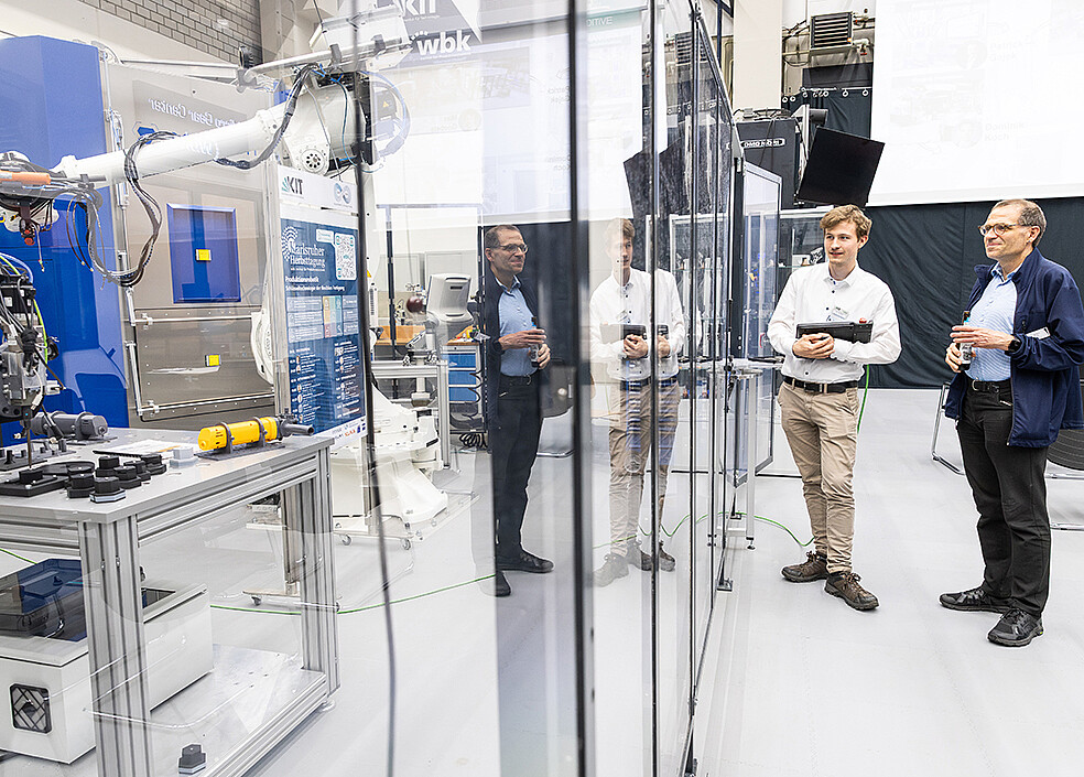 Snapshot of the lab tour: An industry representative and a research assistant talking in front of the transformer cell set up at wbk. (Photo: KIT)