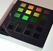 Owing to a structure resembling a nano-grid and diffraction depending on wavelengths, reflexion makes the metallic surface appear to be coloured.