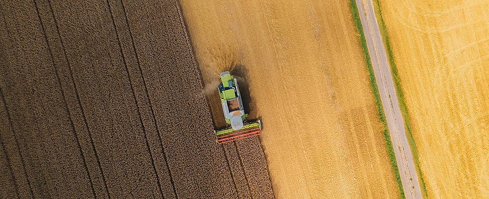 Luftaufnahme einer Landmaschine, die ein Getreidefeld erntet. Das Bild steht symbolisch für den Einsatz neuer, emissionsarmer Technologien wie Wasserstoff-Verbrennungsmotoren in Landmaschinen und anderen Nutzfahrzeugen, wie sie im Projekt PoWer erarbeitet werden. (Bild: orko46 / Pixabay)