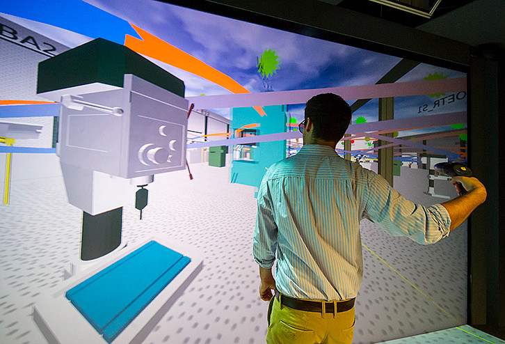 With the appropriate VR equipment, it is possible to explore the generated virtual factory in the CAVE (Computer Automated Virtual Environment). The example shows how a user navigates through a factory with the help of a pointer. (Image: Stadtmarketing Karlsruhe GmbH, photographer Daniel Schoenen)
